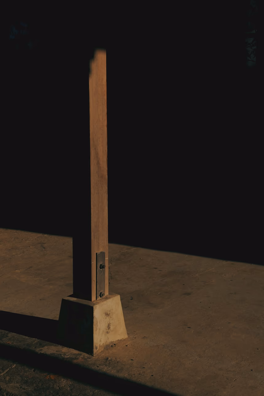 A timber post fixed to a concrete pier with a metal standoff bracket that holds the end of the post clear of the concrete